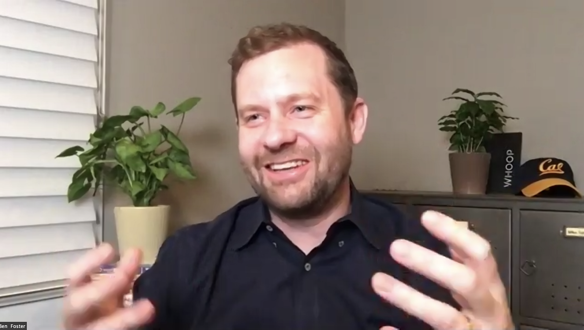 Ben Foster laughing into the camera while giving a talk from his home office.