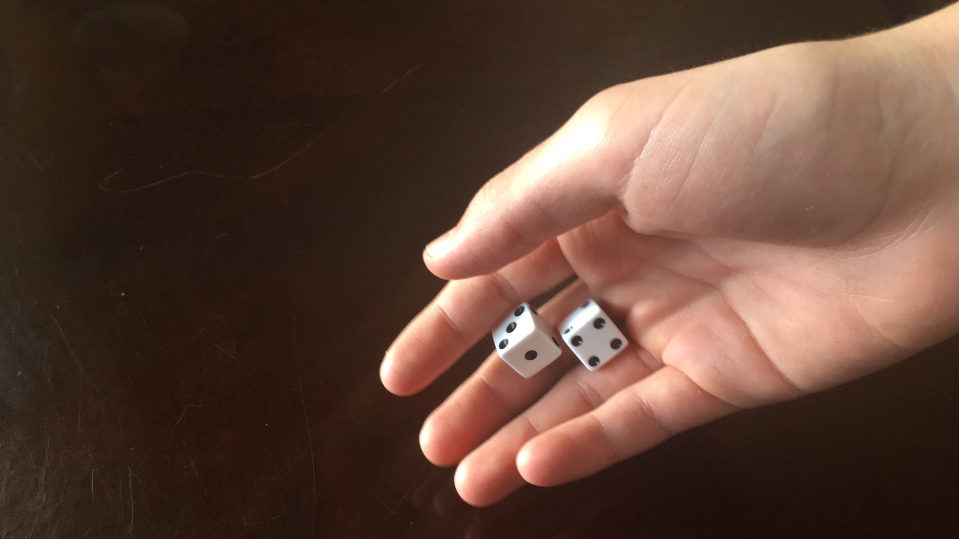 A hand rolling two dice.