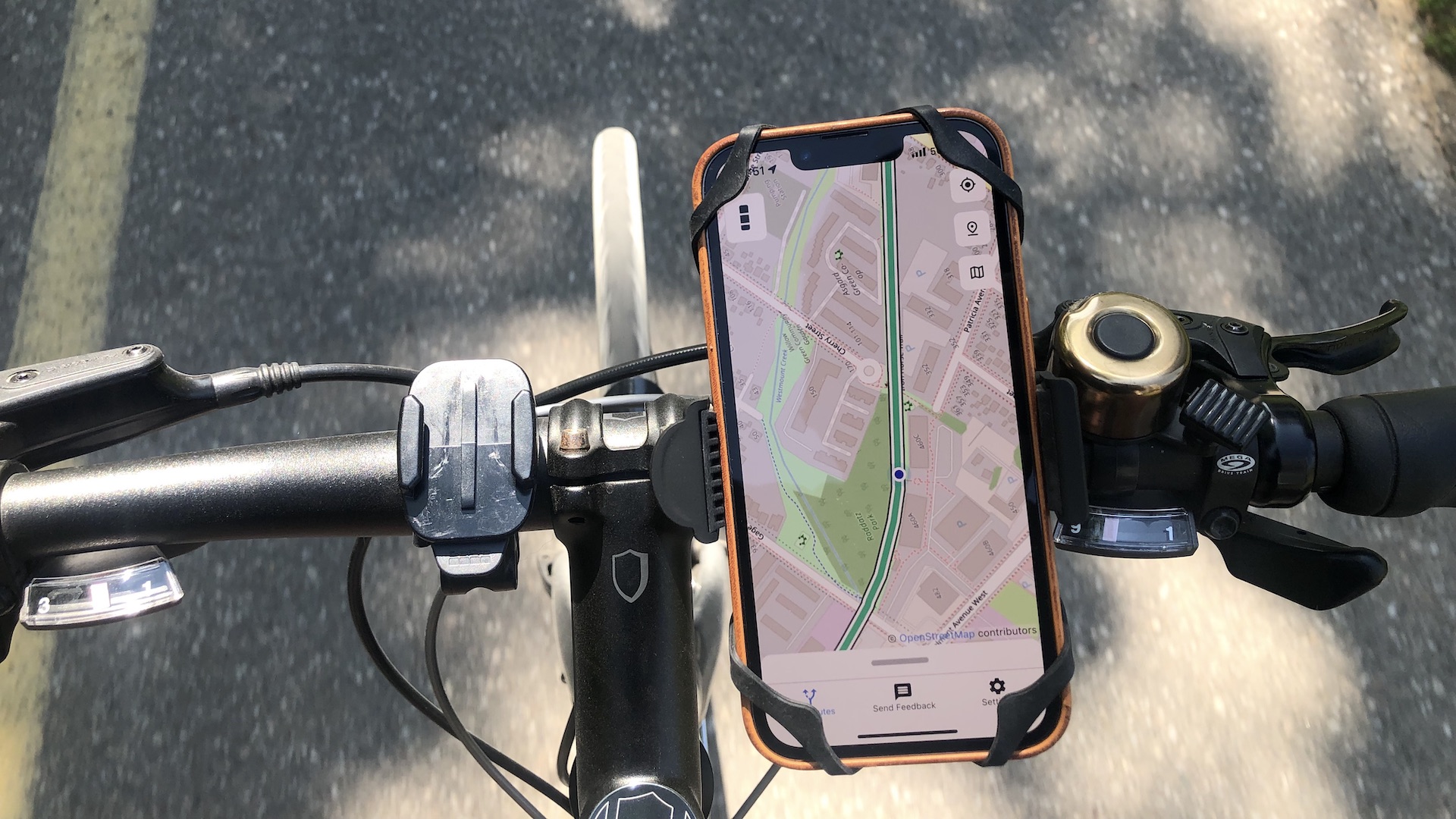 A phone mounted on handlebars of a bike shows a map with a route on it