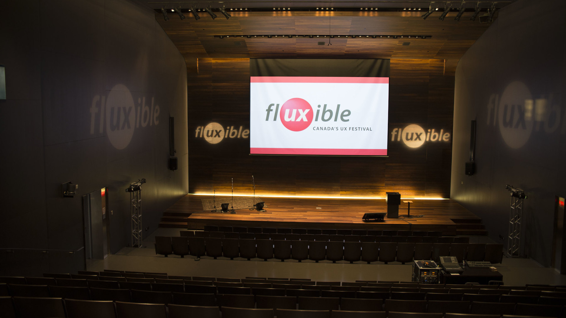 The Fluxible logo on a screen on above the stage in an empty theatre.