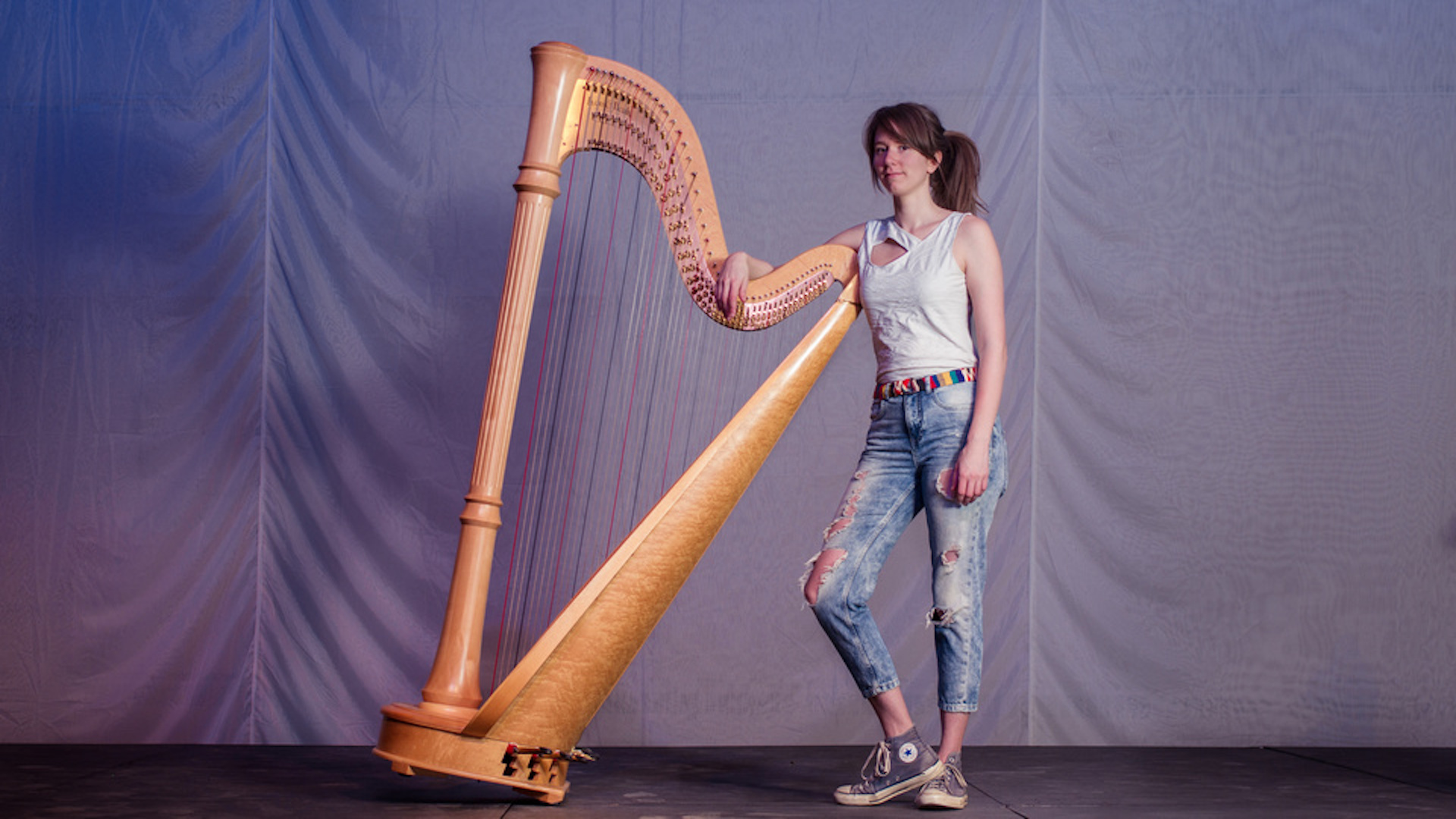 Grace Scheele standing next to her harp. 