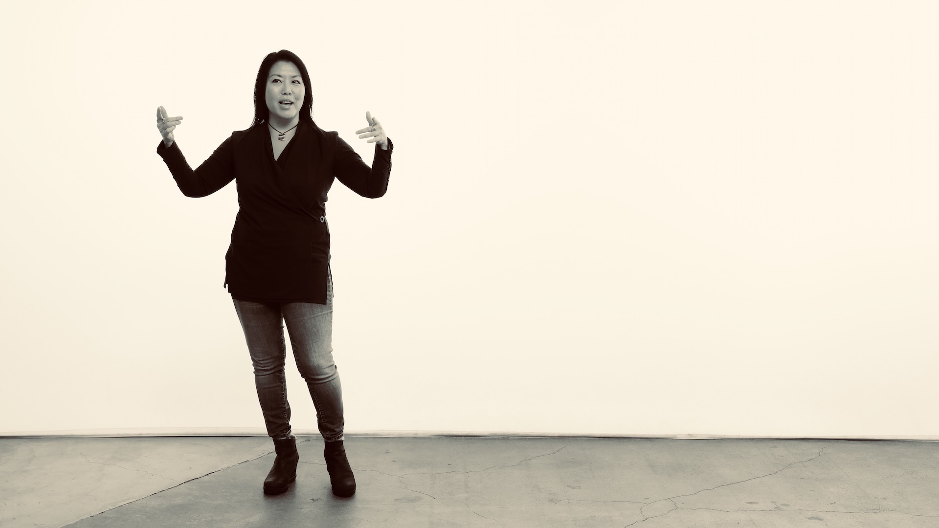 Kelly Goto stands in front of a blank wall.