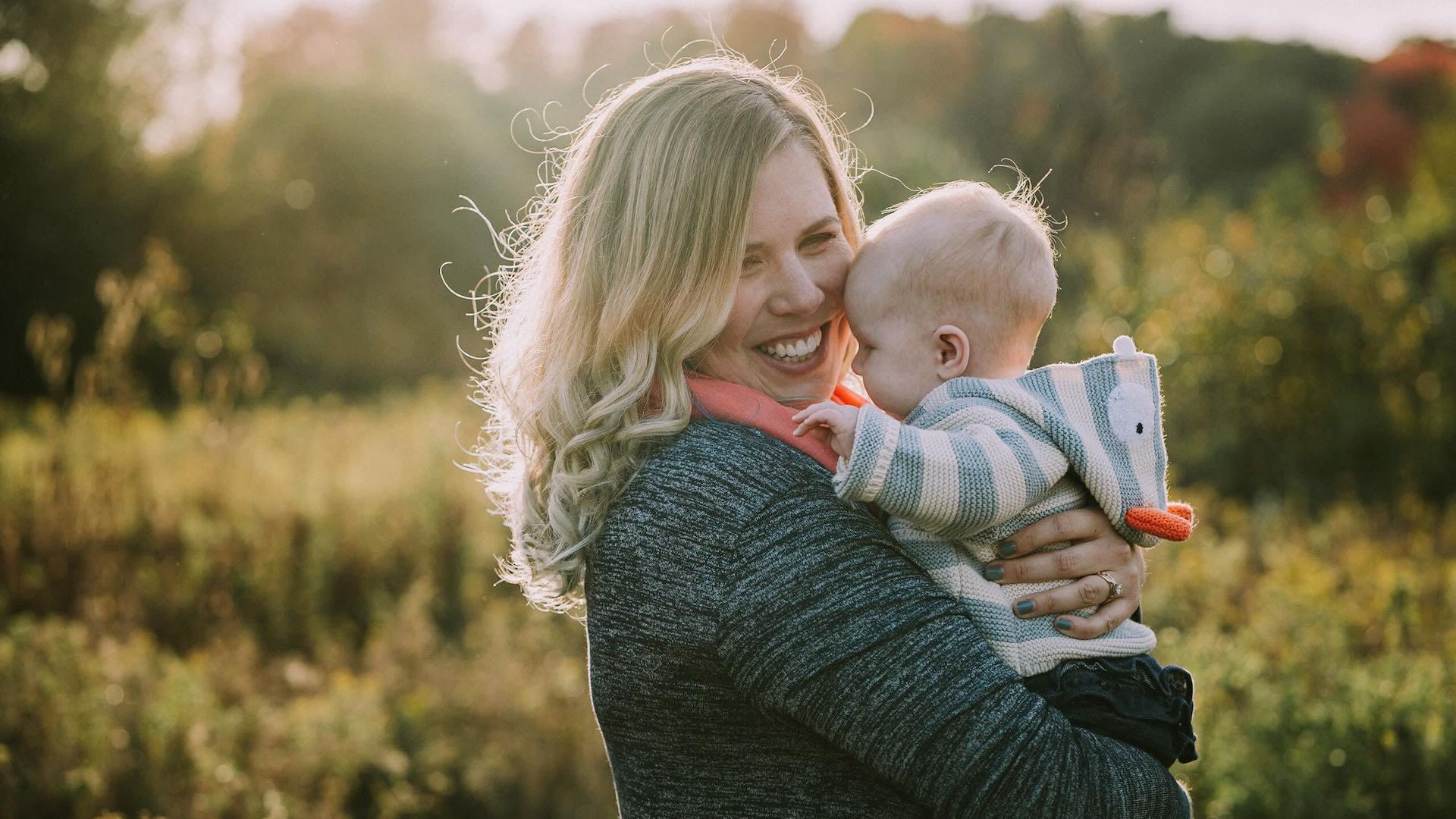 Zeitspace UX designer Megan Pollock stands in a field holding her infant daughter.