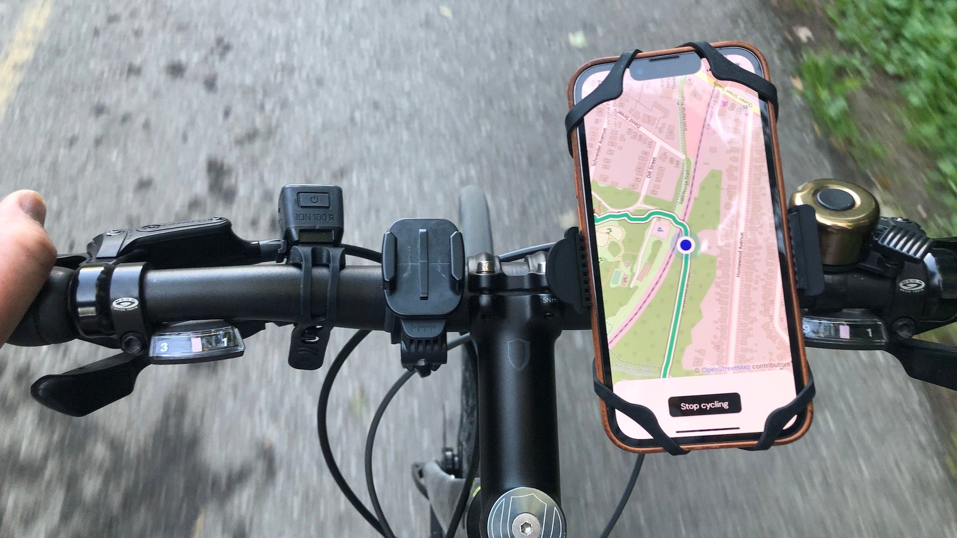 A bicyclist's view looking down at a phone mounted on bike handlebars. The phone's screen shows a map with a marked route on it.