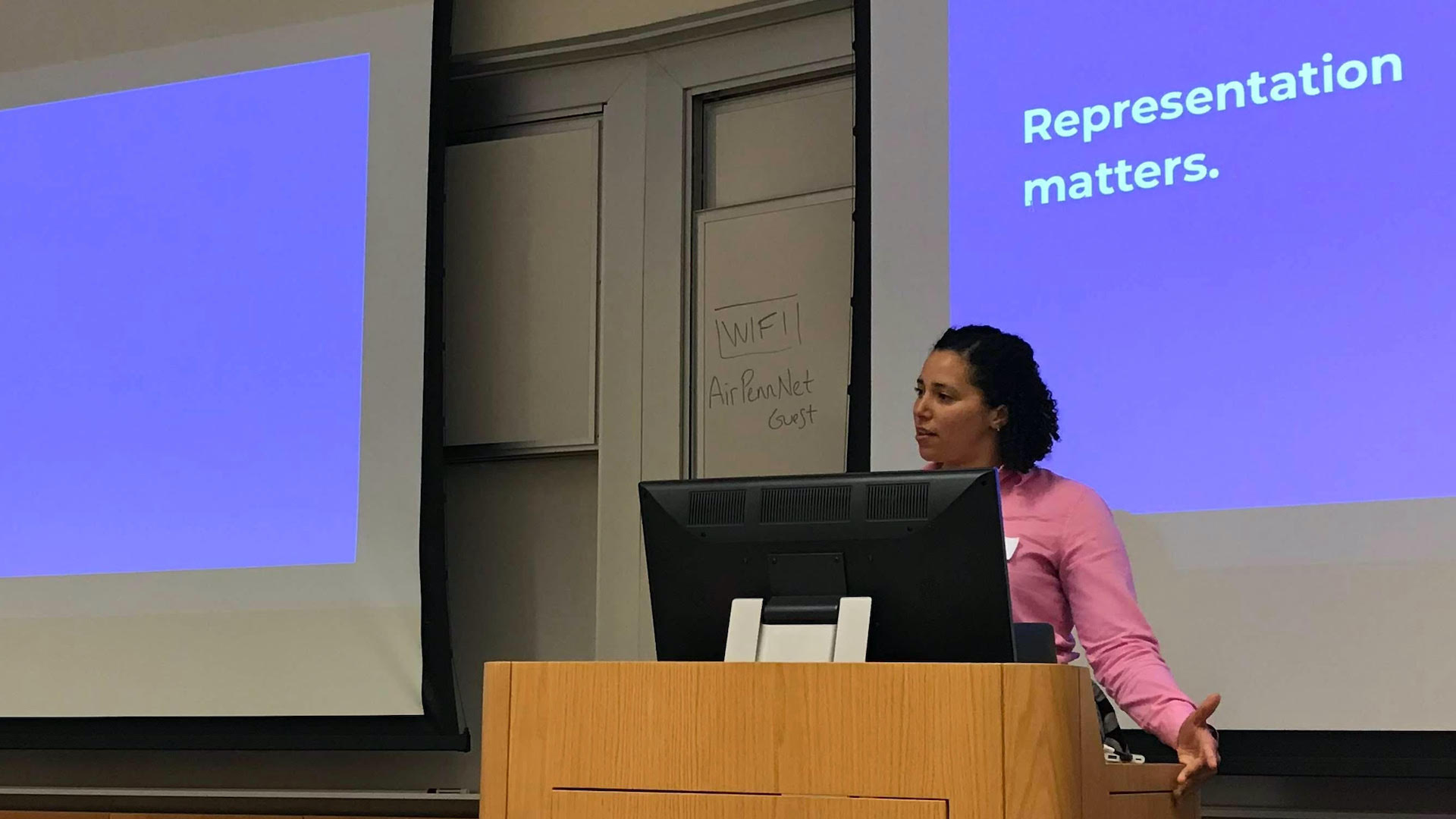 Sara Hall talks at a podium. Behind her is a screen with text 