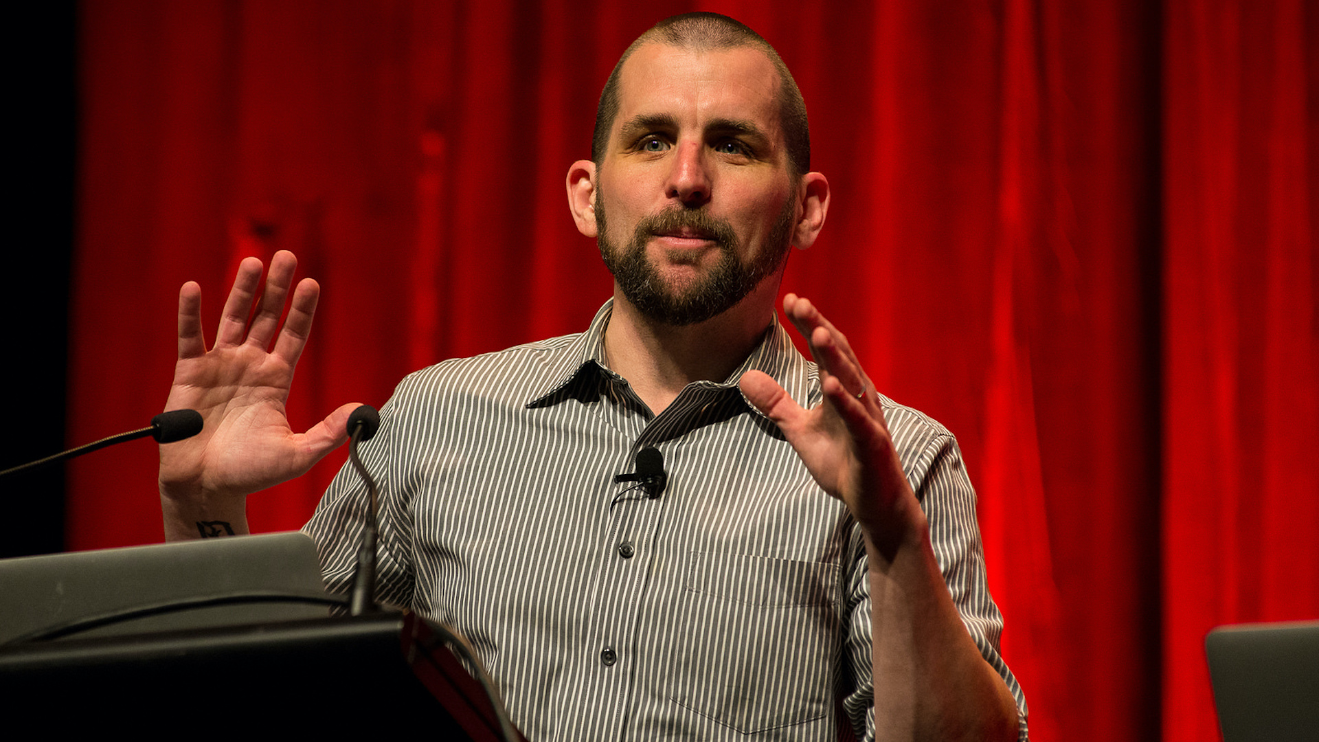 Scott Berkun stands at a podium with a laptop.