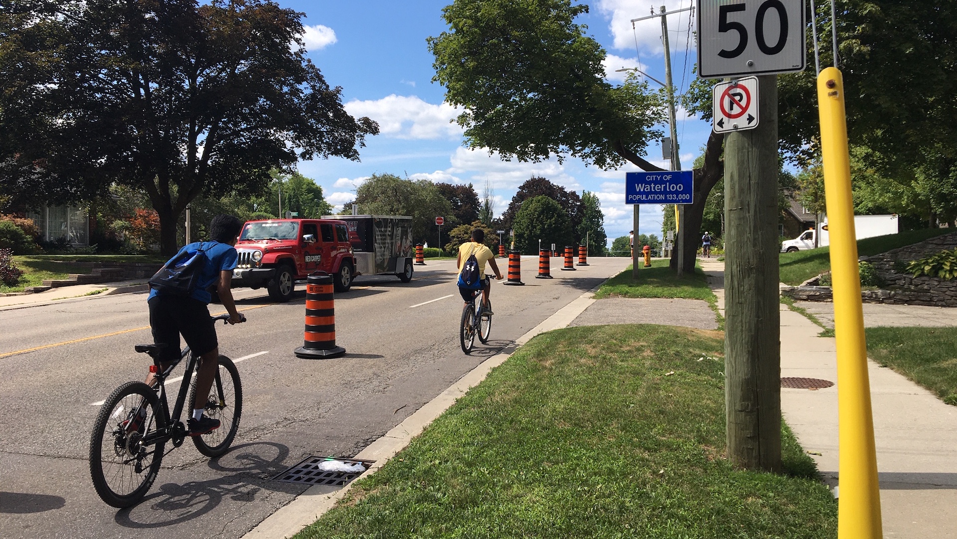 Two cyclists on a road, separated by construction barrels to protect them from traffic in Waterloo, Ontario.