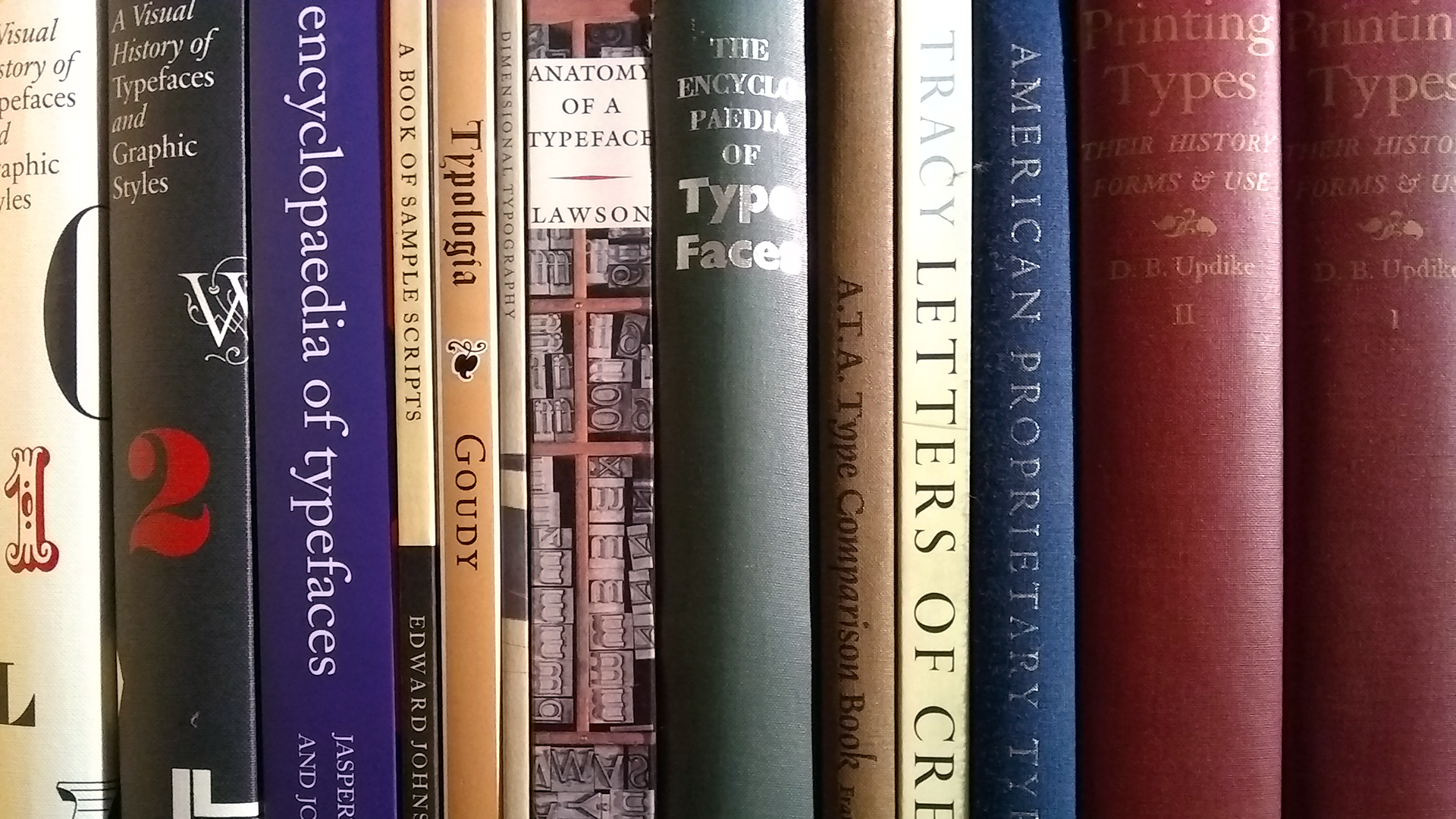 Book spines lined up on a book shelf.