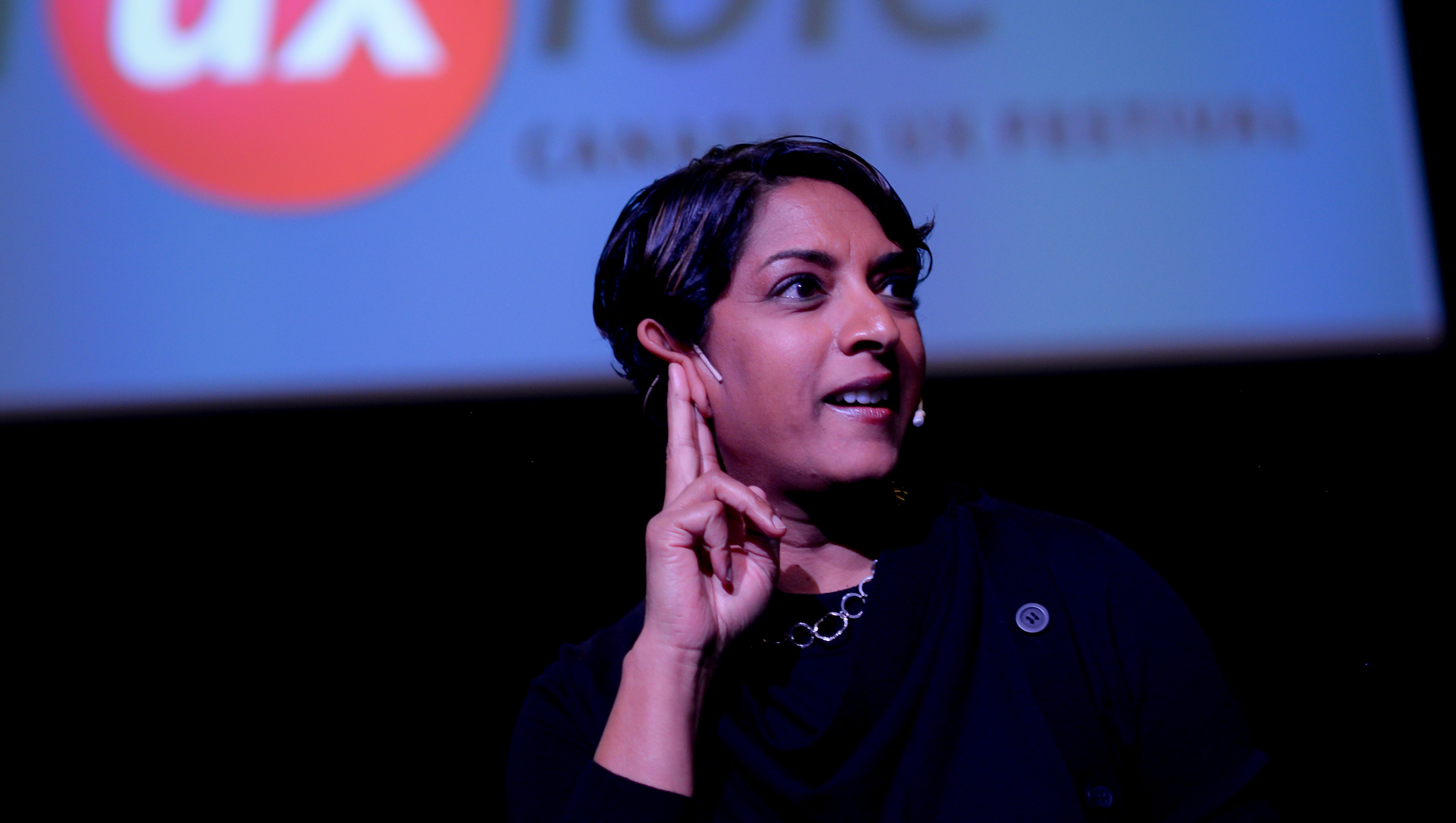 Meena Kothandaraman points up while standing on a stage during Fluxible 2019.