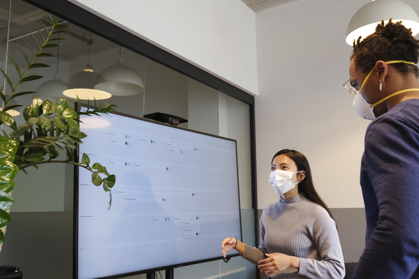 a man and a woman wearing masks plan product features on a virtual agile board