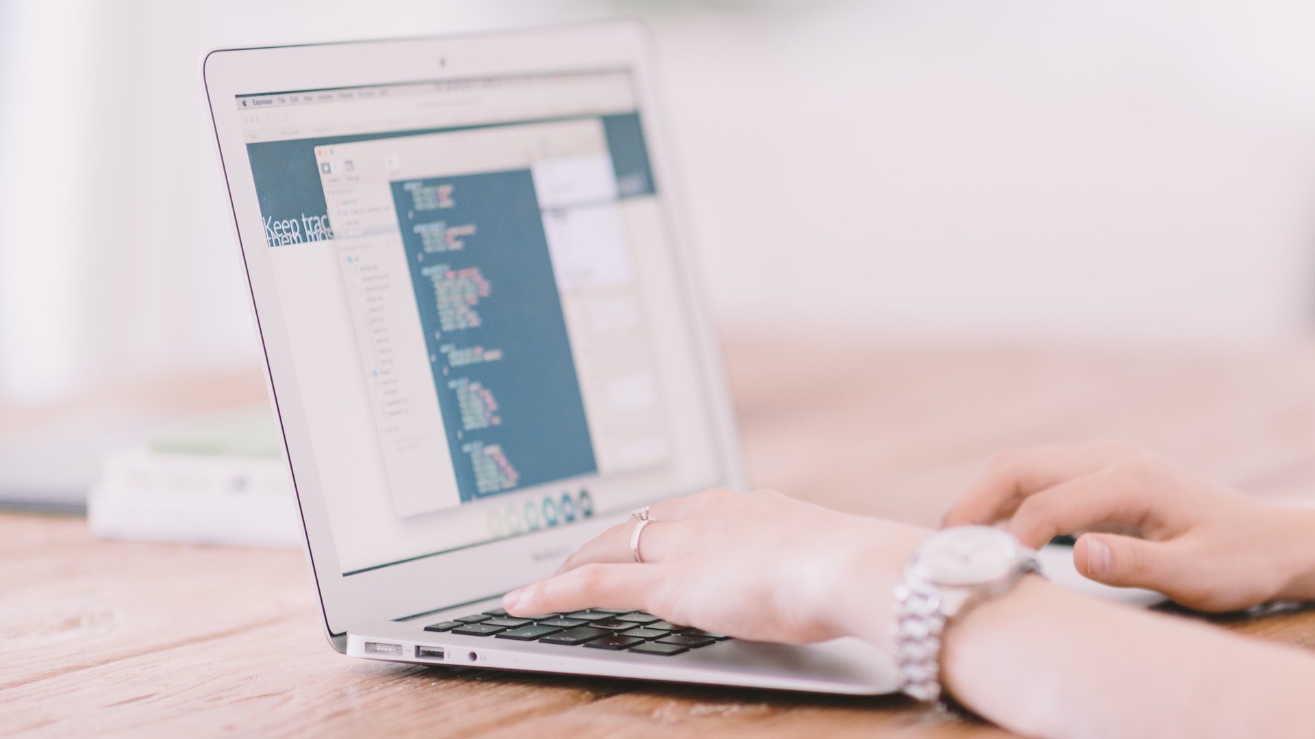 A woman works on a laptop displaying software development code.