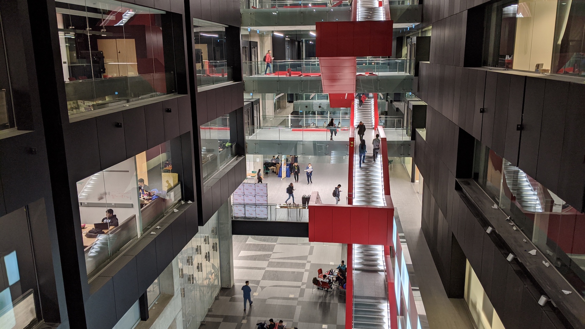People walk up and down a red floating staircase at the University of Waterloo during StarterHacks in January 2020.