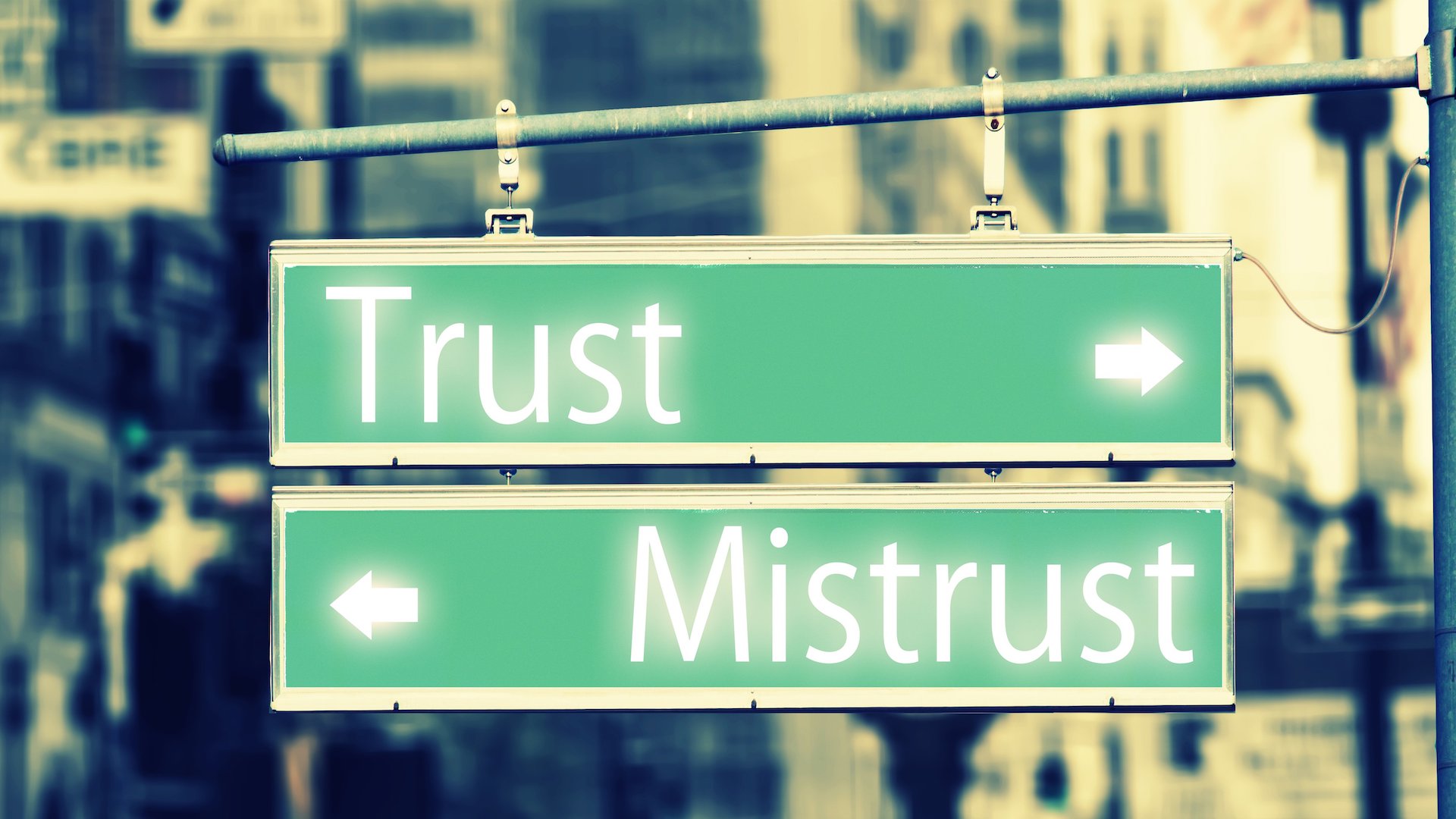 Two green street signs, one that says trust, another that says mistrust, with an arrow pointing in opposite directions.