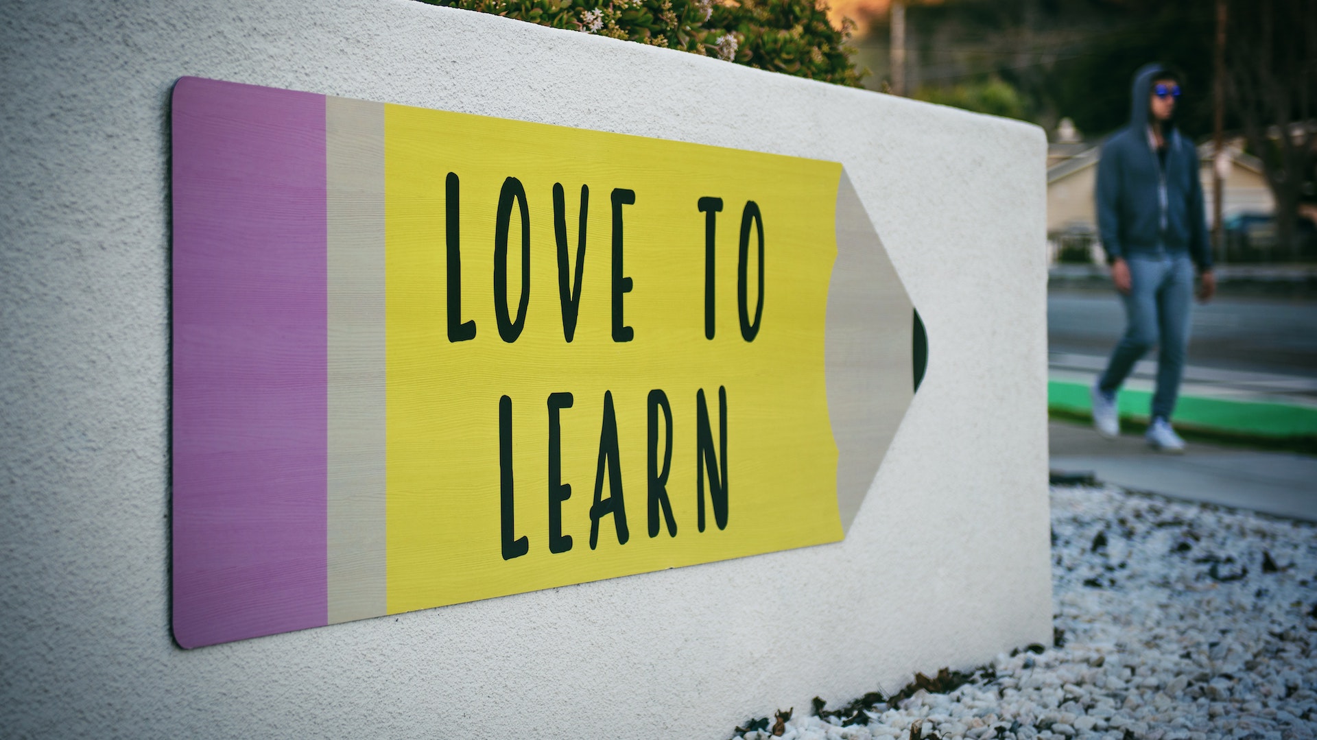 A cartoon pencil that's yellow with a pink eraser. Text on pencil: Love to learn.